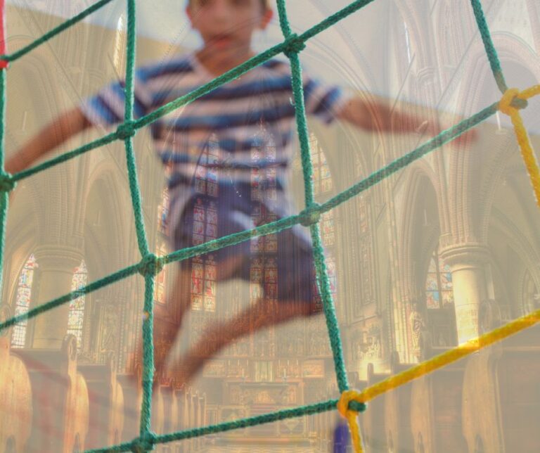 young boy on trampoline with a screened image of the inside of a Catholic Church as background