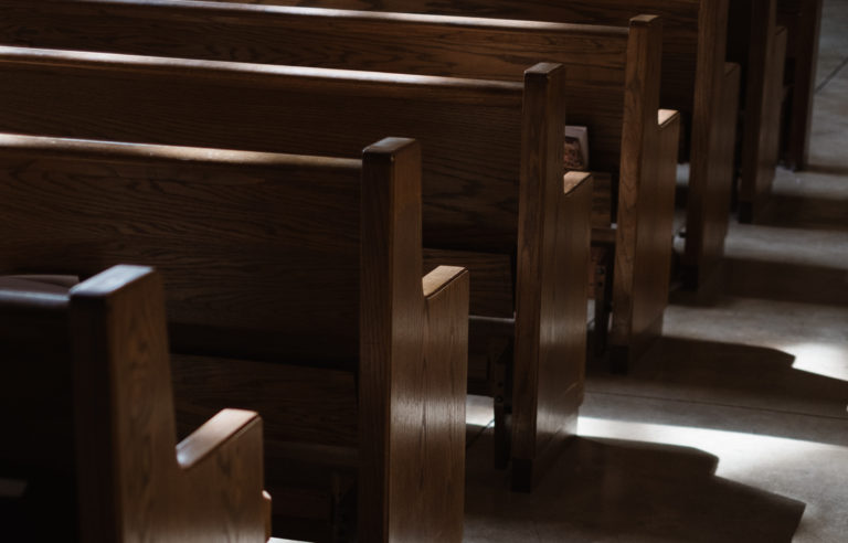 A cropped view of empty wooden pews in a Church